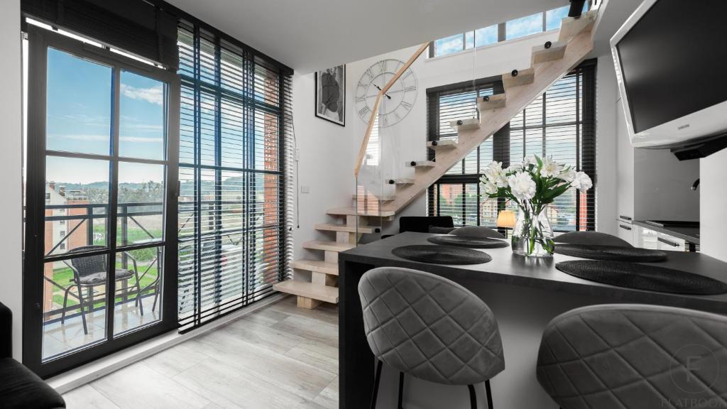 a dining room with a staircase and large windows at Flatbook - City Center SPA Apartments Dwie Motlawy in Gdańsk