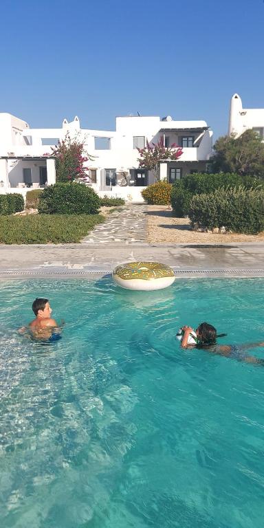 dwie osoby w wodzie w basenie w obiekcie Rosanna kite apartments by the sea & pool with sunset w mieście Pounda