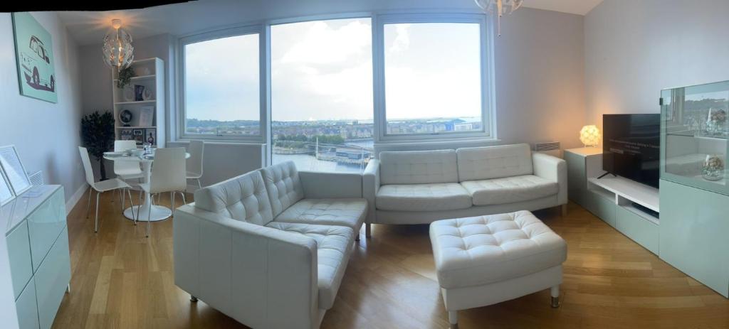 una sala de estar con muebles blancos y ventanas grandes. en Luxury 8th Floor Apartment with Stunning Views, en Chatham