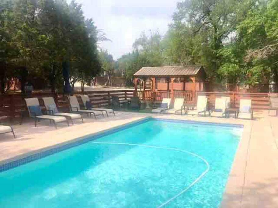 a swimming pool with chairs and a gazebo at The Armadillo Cabin - Cabins At Rim Rock in Austin