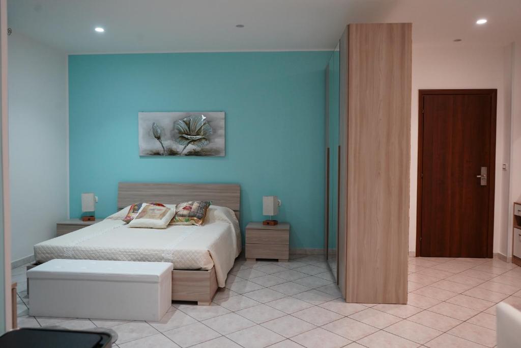 1 dormitorio con cama y pared azul en Casa di Suele, en Solarino
