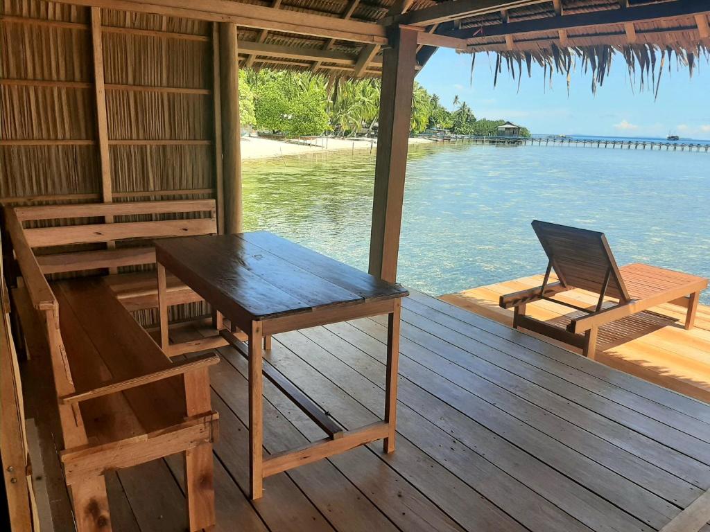 a table and chairs sitting on a deck with the water at Frances Homestay - Raja Ampat in Pulau Mansuar