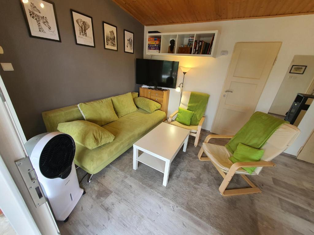 a living room with a green couch and chairs at Orfűi Kisház in Orfű