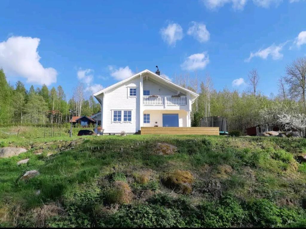 une maison blanche au-dessus d'un champ herbeux dans l'établissement Stunning Tiny House Tree of Life at lake Skagern, à Finnerödja