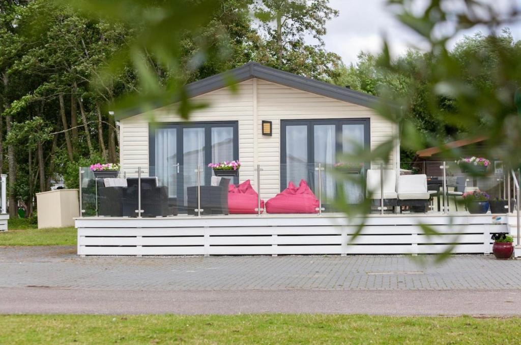 a small house with red pillows in the front at Spacious Homely Lakeside Lodge close to the Beaches in Chichester