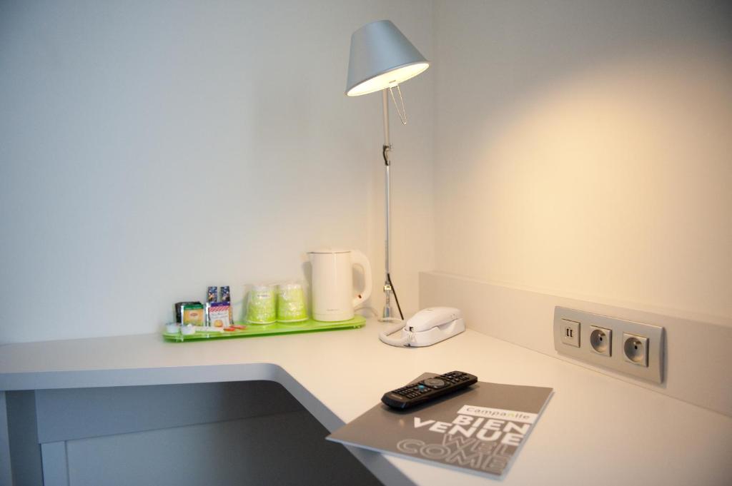 a desk with a lamp and a remote control on it at Campanile Limoges Centre - Gare in Limoges