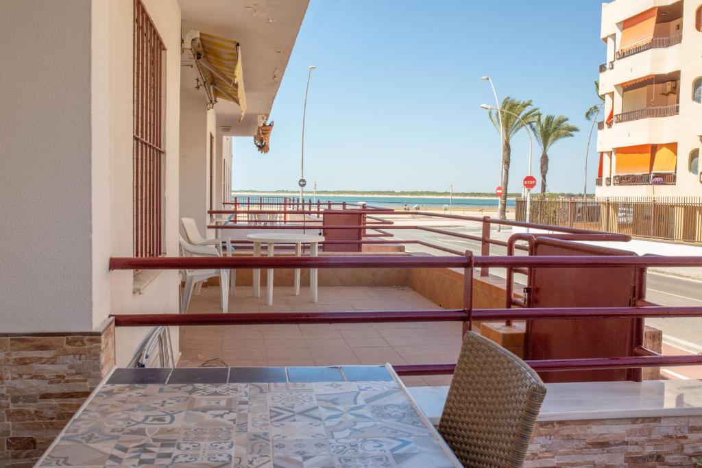 een balkon met een tafel en stoelen en uitzicht op het strand bij El Rincón de Soraya in Sanlúcar de Barrameda