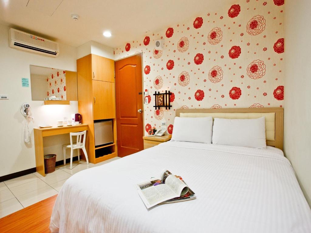 a bedroom with a bed with a book on it at Green Park Commercial Hotel in Tainan