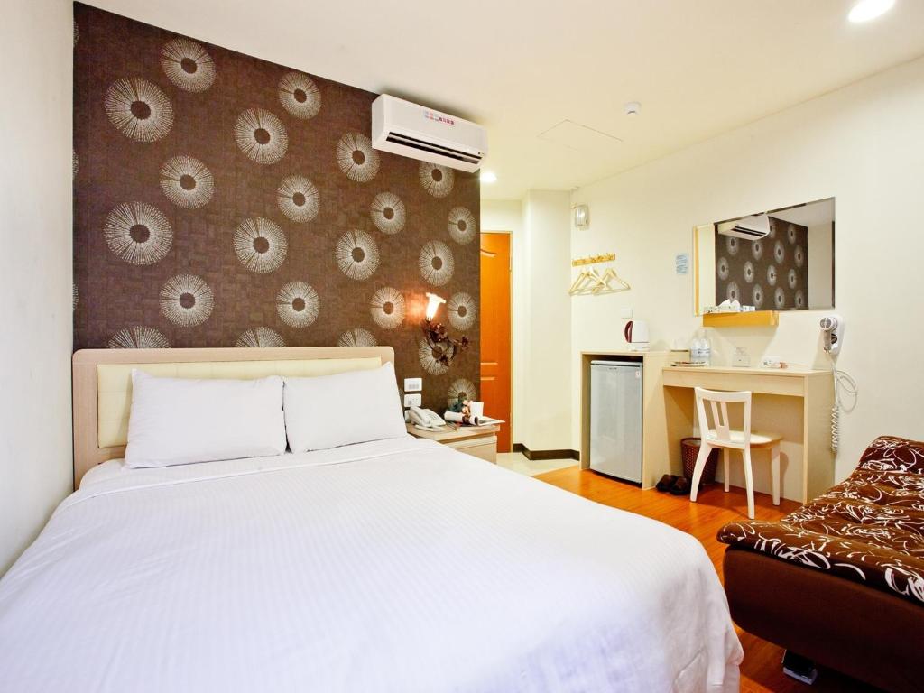1 dormitorio con cama blanca y escritorio en Green Park Commercial Hotel en Tainan