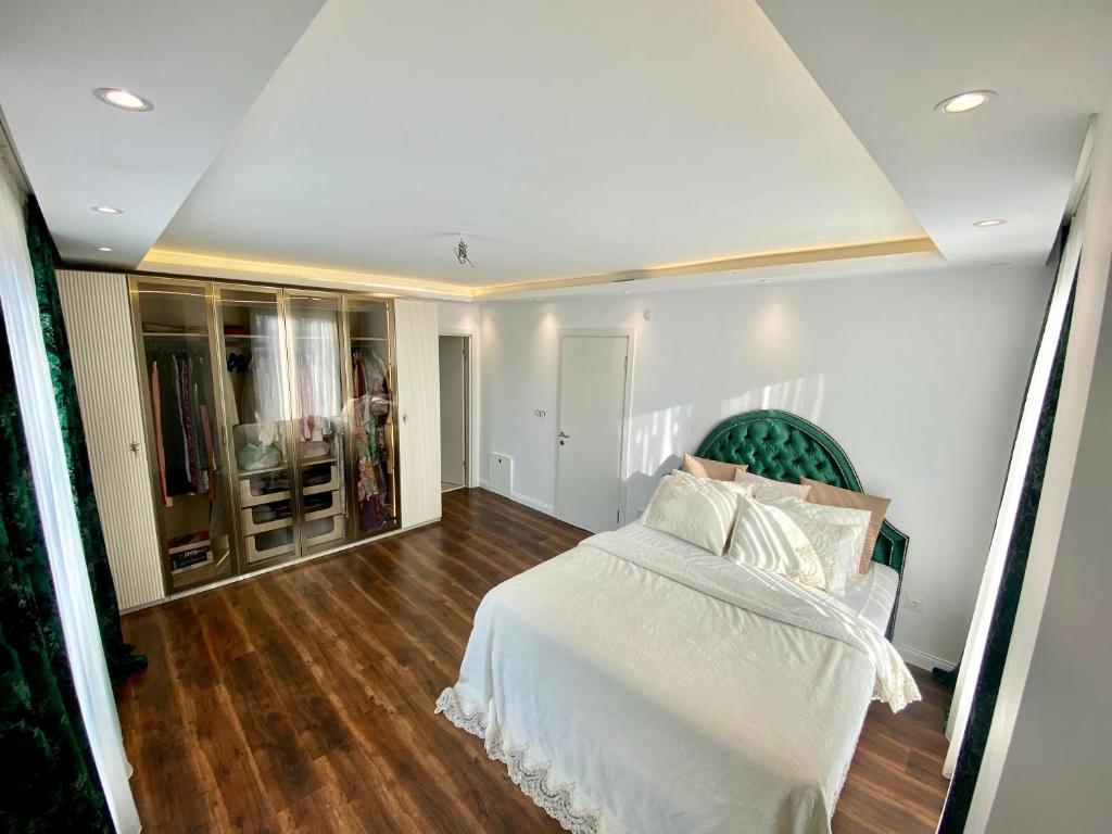 Schlafzimmer mit einem weißen Bett und Holzböden in der Unterkunft Wonderful Villa Airport 5 minutes in Arnavutköy