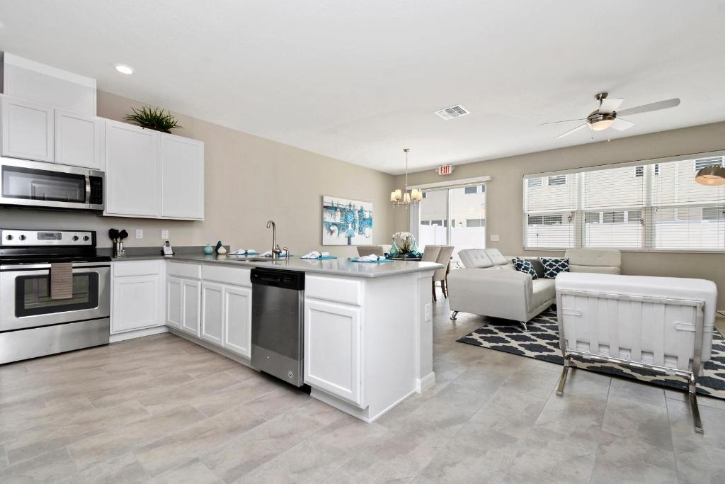 uma cozinha com armários brancos e uma sala de estar em Stunning 4 Bd w/ GameRoom Close to Disney 5110K em Kissimmee