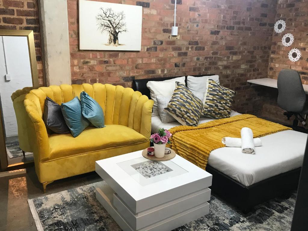 a living room with a yellow couch and a table at Maboneng Craftsmanship place in Johannesburg