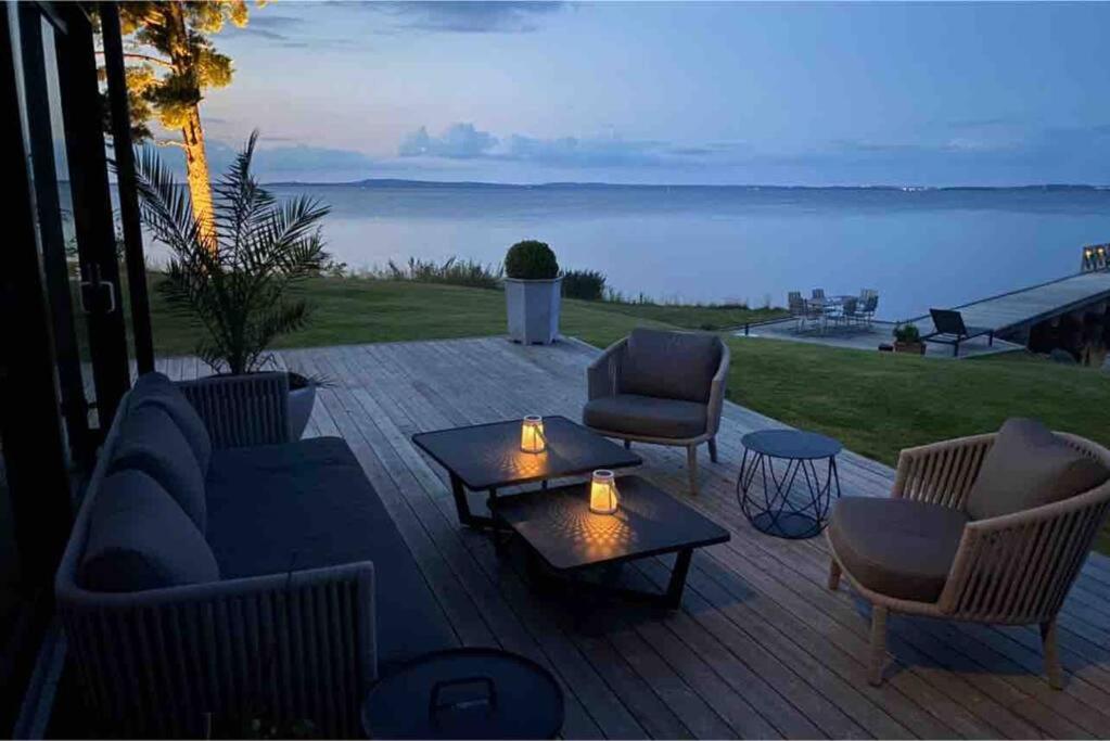 a patio with chairs and tables and a view of the water at Stylish lake view house in Vadstena