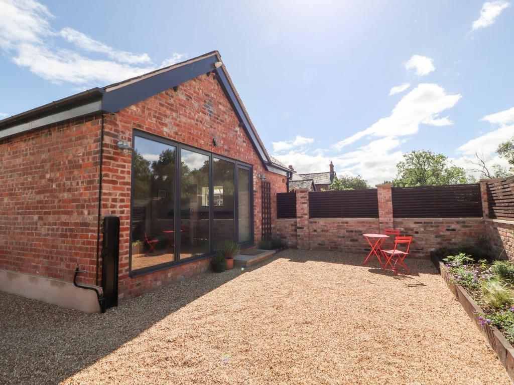 a brick house with a patio and a table at Swallow Cottage in Sandbach