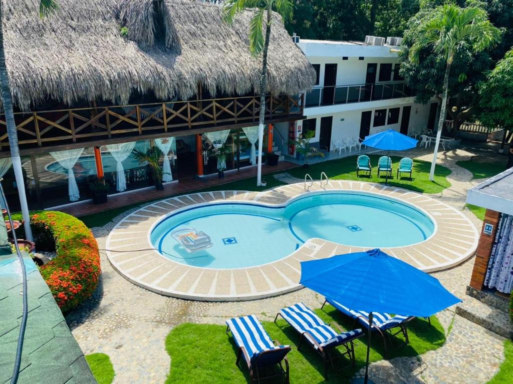 a swimming pool with chairs and umbrellas in front of a building at Hotel Randuky Tayrona in El Zaino