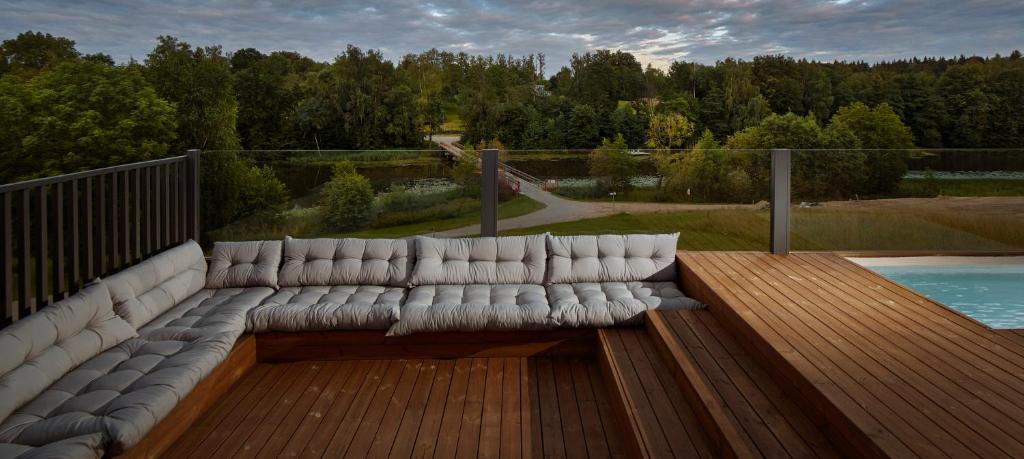 eine Couch auf einer Holzterrasse neben einem Pool in der Unterkunft 3kampai in Molėtai