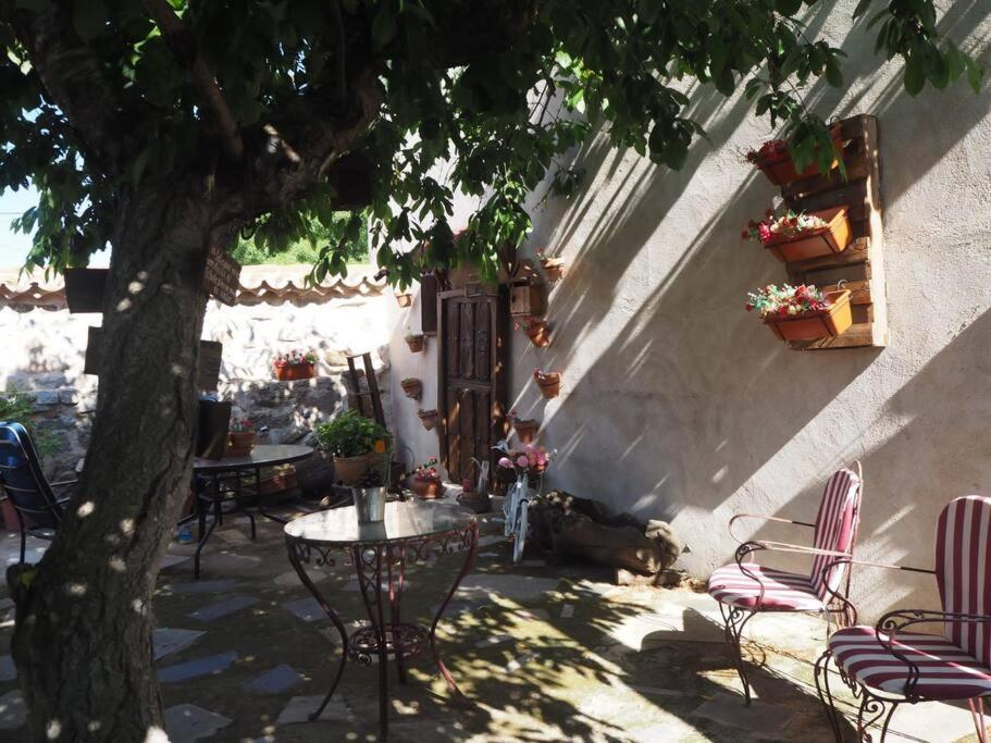 a patio with a table and chairs and a tree at Casa Rural El Guindo in Avila