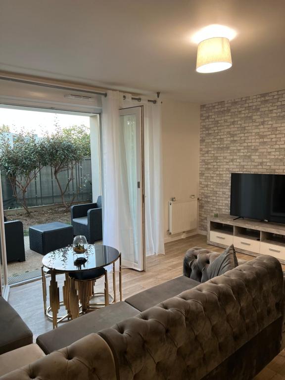 a living room with a couch and a table at Appartement rez de chaussée avec parking privé in Orléans