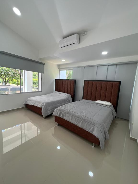 Duas camas num quarto com pisos brancos e janelas em FINCA LUXURY SAN JERONIMO em Medellín