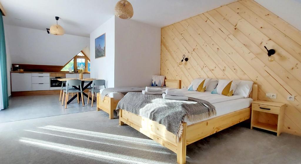 een slaapkamer met 2 bedden en een houten muur bij Tatra Apartament in Jurgów