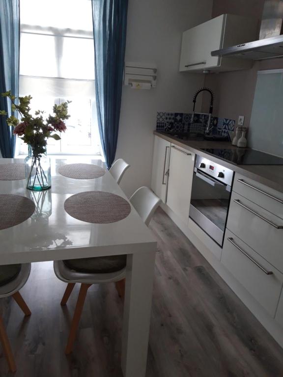 una cocina con mesa y sillas blancas en Les Apparts' Hotel du Canal, en Châteaulin