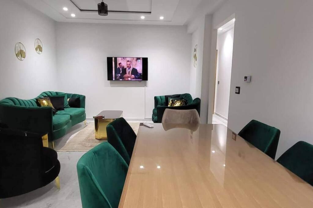 een woonkamer met een houten tafel en groene stoelen bij Riadh Andalous: Superbe S+2 in Ariana