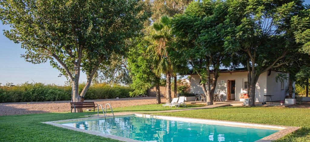 una piscina di fronte a una casa alberata di Preciosa y confortable casa de campo con piscina y chimenea a Carmona