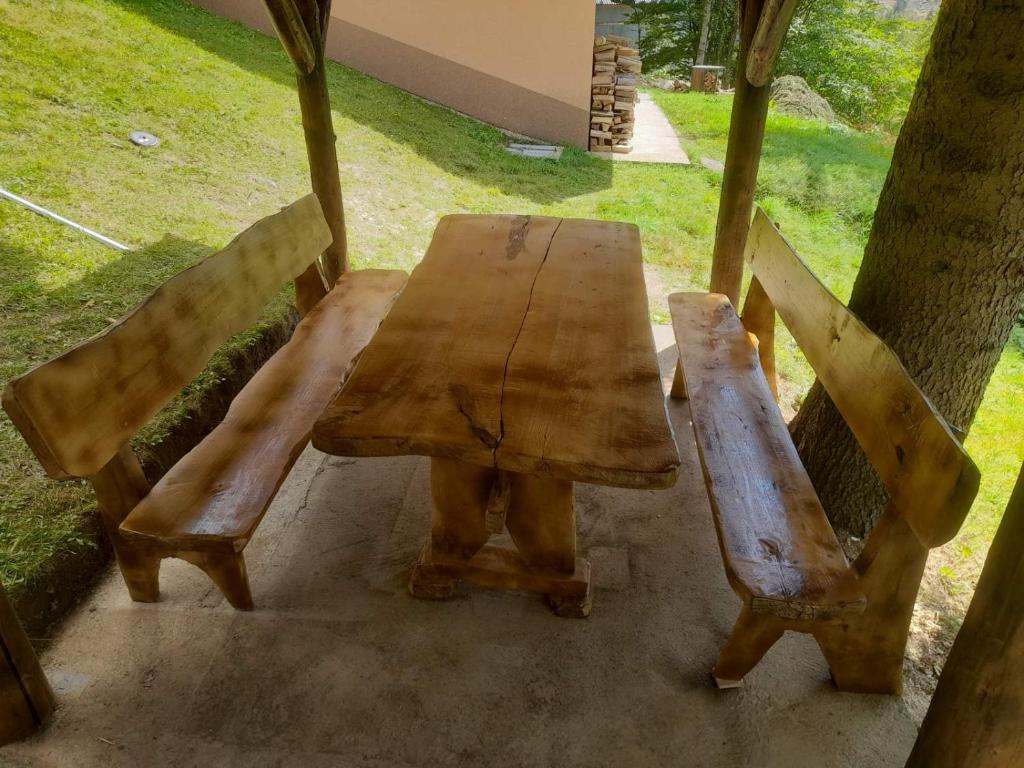 a wooden table and two benches sitting next to a tree at Vikendica Čeperković #2 in Kopaonik