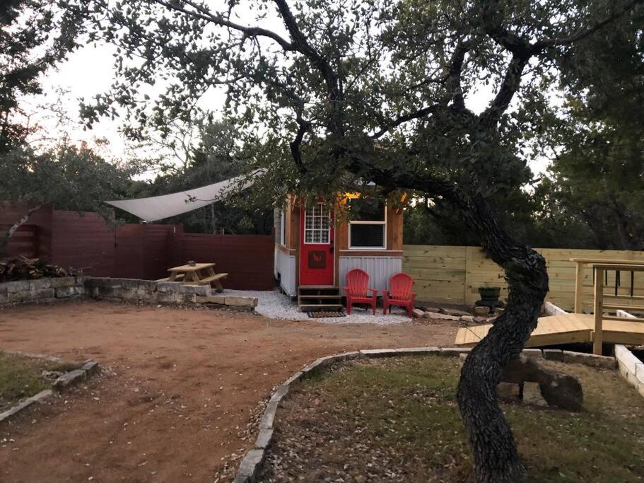 a tiny house with a red door and red chairs at Fox Tiny Home - The Cabins at Rim Rock in Austin