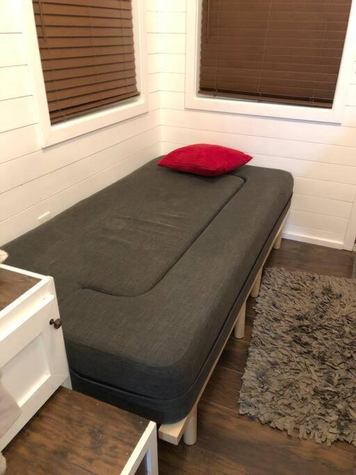 a bed in a room with a red pillow on it at Fox Tiny Home - The Cabins at Rim Rock in Austin