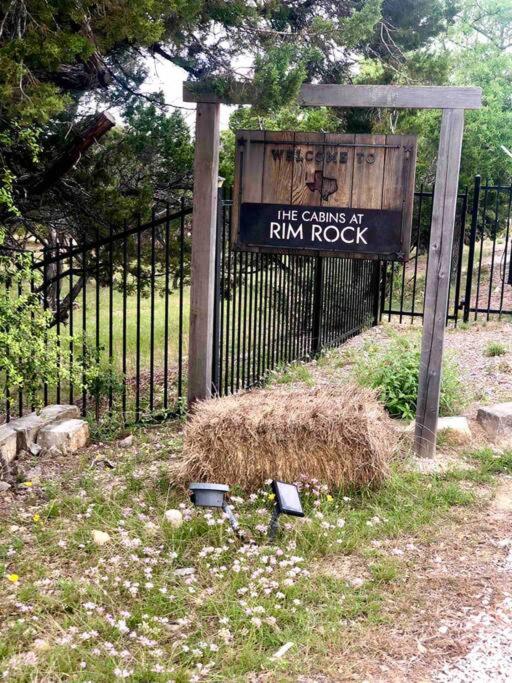 a sign in front of a fence with a pile of hay at Fox Tiny Home - The Cabins at Rim Rock in Austin