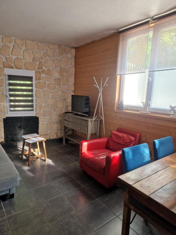 a living room with a red couch and a table at Le Syma, en plein centre ville in Le Bourg-dʼOisans