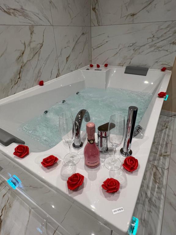 Diamond Apartment Piran FREE PARKING في بيران: حمام مع حوض مع كؤوس النبيذ والورود