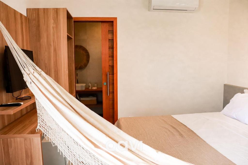 eine Hängematte in einem Schlafzimmer mit einem Bett in der Unterkunft Casa Kairós no Shamballa by Qavi in São Miguel do Gostoso