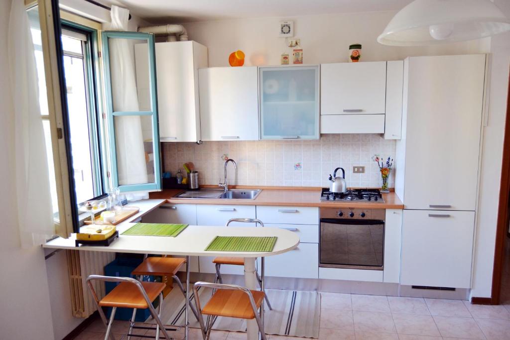 una cucina con mobili bianchi, tavolo e sedie di [Centro storico] Vulcano1, Bilocale strategico tra Milano, Como, fiere a Turate