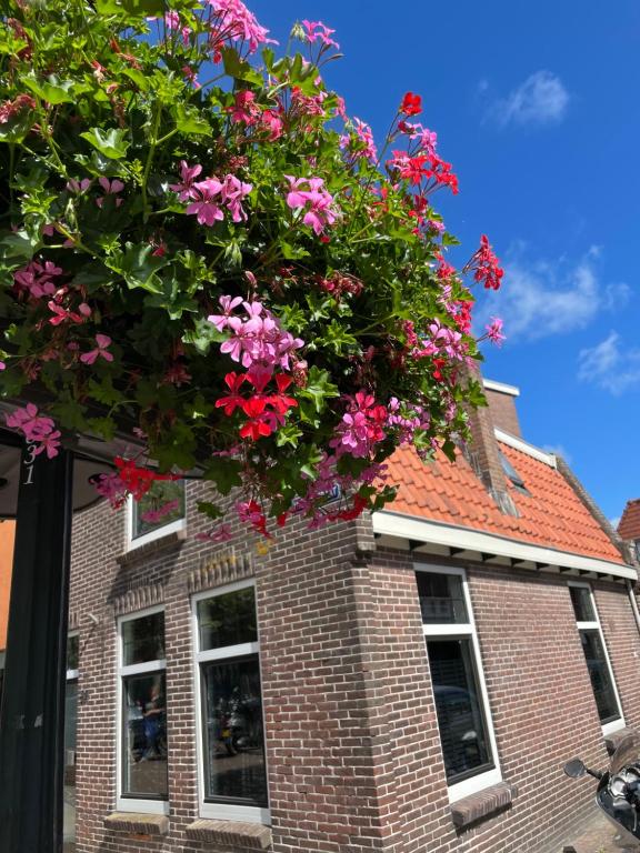 une corbeille suspendue de fleurs sur un bâtiment en briques dans l'établissement Vakantiehuis in het hart van Medemblik, à Medemblik