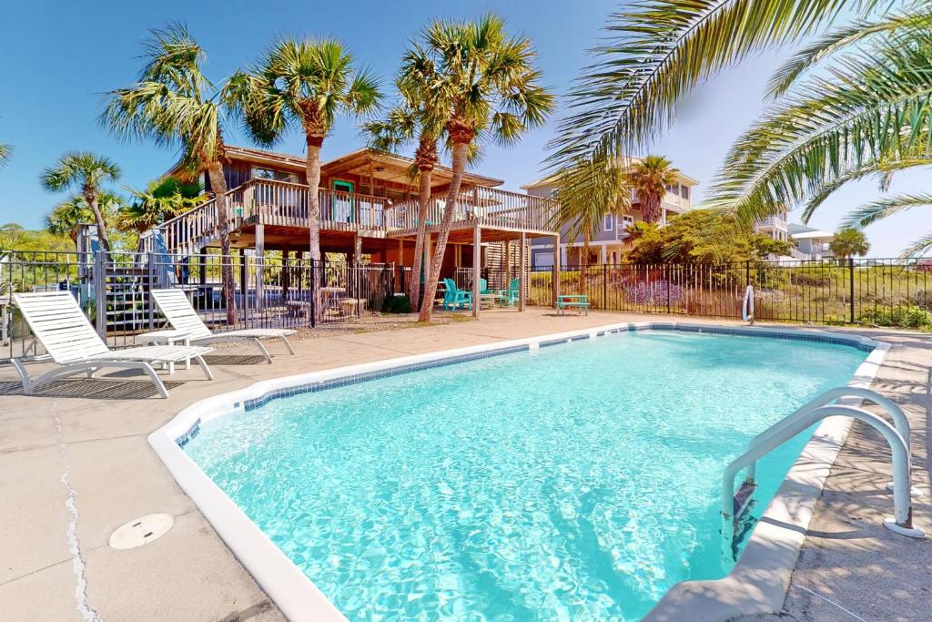 a swimming pool in front of a house with palm trees at Somerset in St. George Island