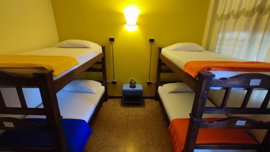 a room with three bunk beds and a light on the wall at Macondo Hostel in San Gil