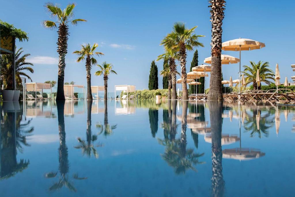 a pool of water with palm trees and umbrellas at Radisson Blu Resort & Spa in Split