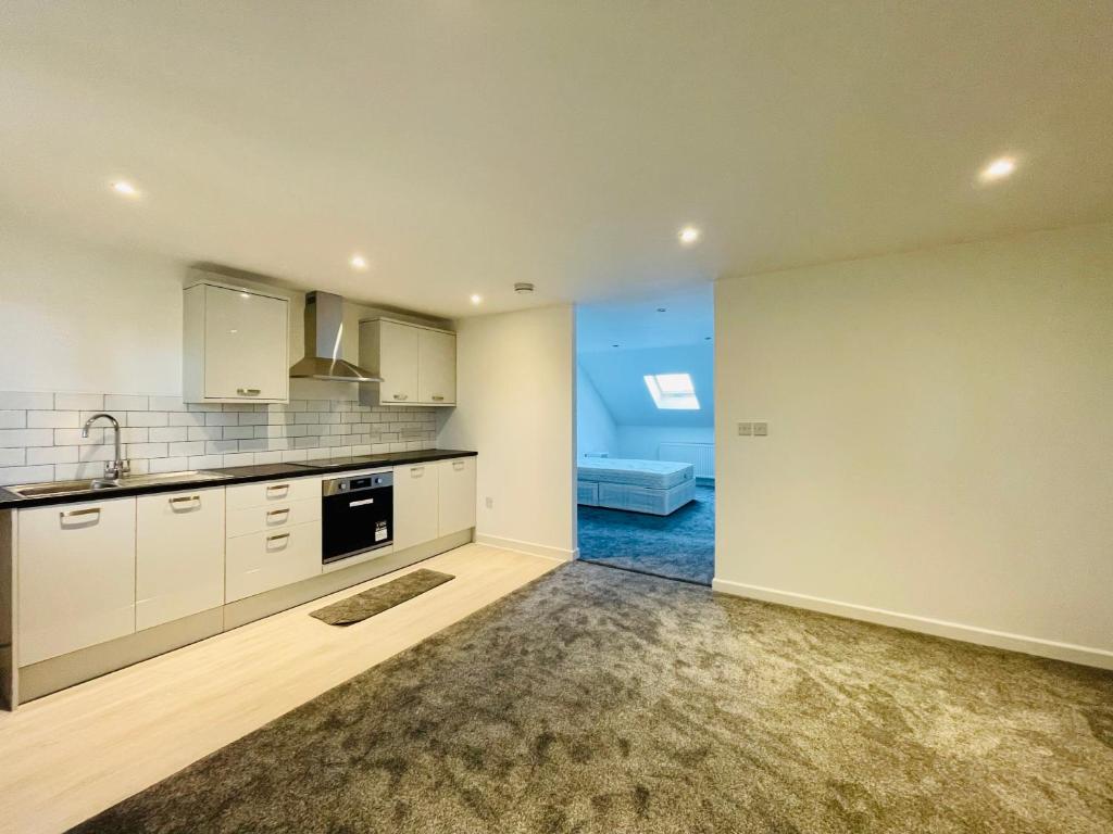 a kitchen with white cabinets and a couch in the background at Layrek London 1 bedroom flat in London