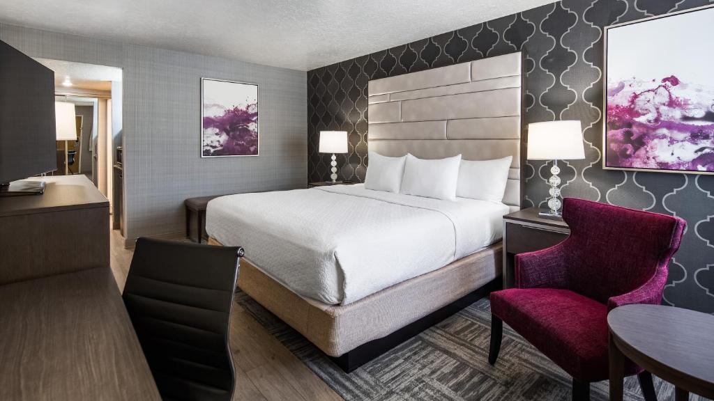 a hotel room with a bed and a desk and a chair at Abbey Inn Cedar City in Cedar City