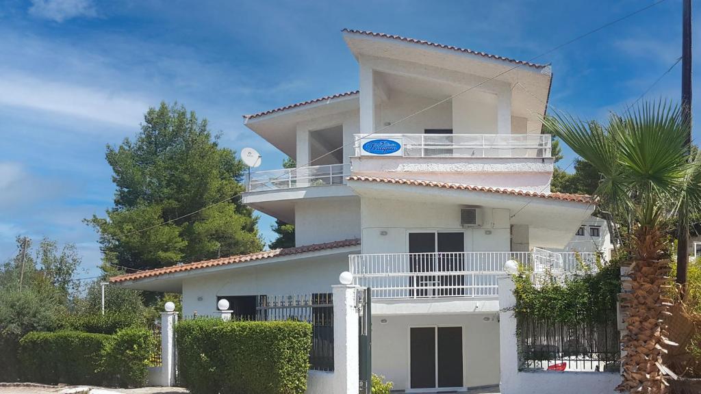 a white house with a balcony and a palm tree at Studio Kalypso in Arkitsa