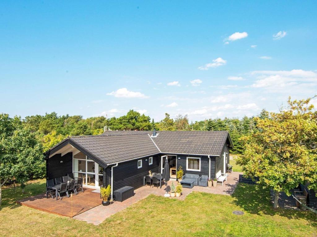 a black house with a patio and a yard at 6 person holiday home in Skjern in Halby