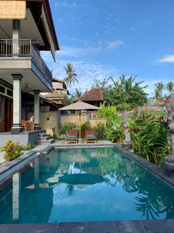 a swimming pool in front of a house at Bhakti Ubud Villa in Ubud