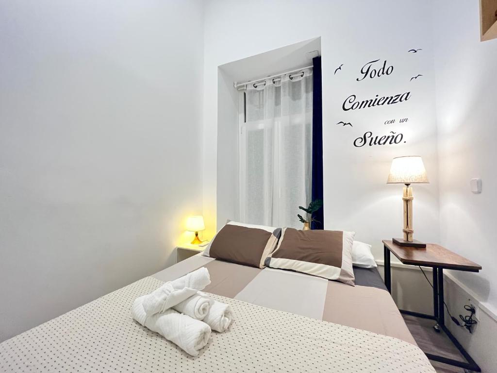 a white bedroom with a bed and a window at Ile Atocha Exterior Olivar in Madrid