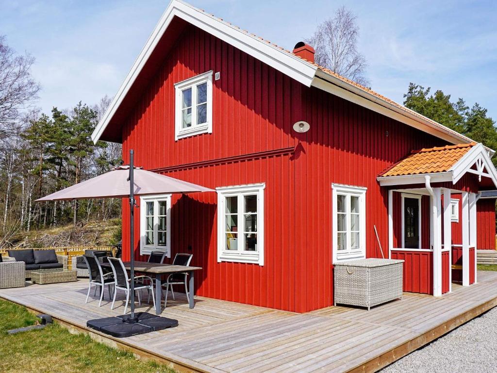 a red house with a table and chairs on a deck at Holiday home Grebbestad IX in Grebbestad