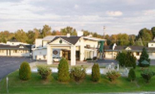 a large white house in a yard with trees at Colonie Inn and Suites in Latham