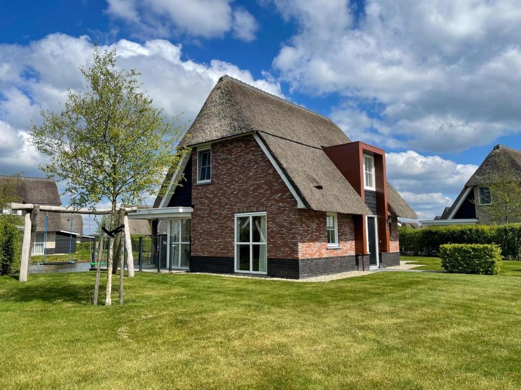 una casa de ladrillo con techo de gambrel en Beautiful villa with wellness in a holiday park on the Tjeukemeer, en Delfstrahuizen