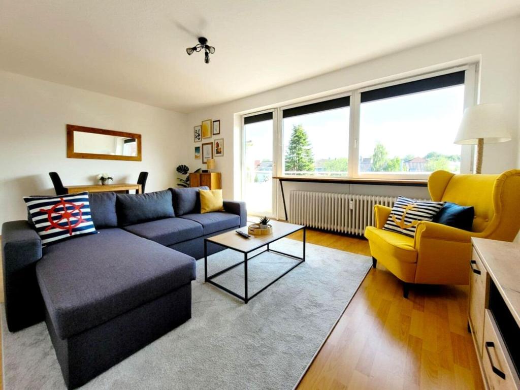 Una sala de estar con un sofá azul y sillas amarillas. en Stilvolles Apartment mit Balkon, en Wilhelmshaven