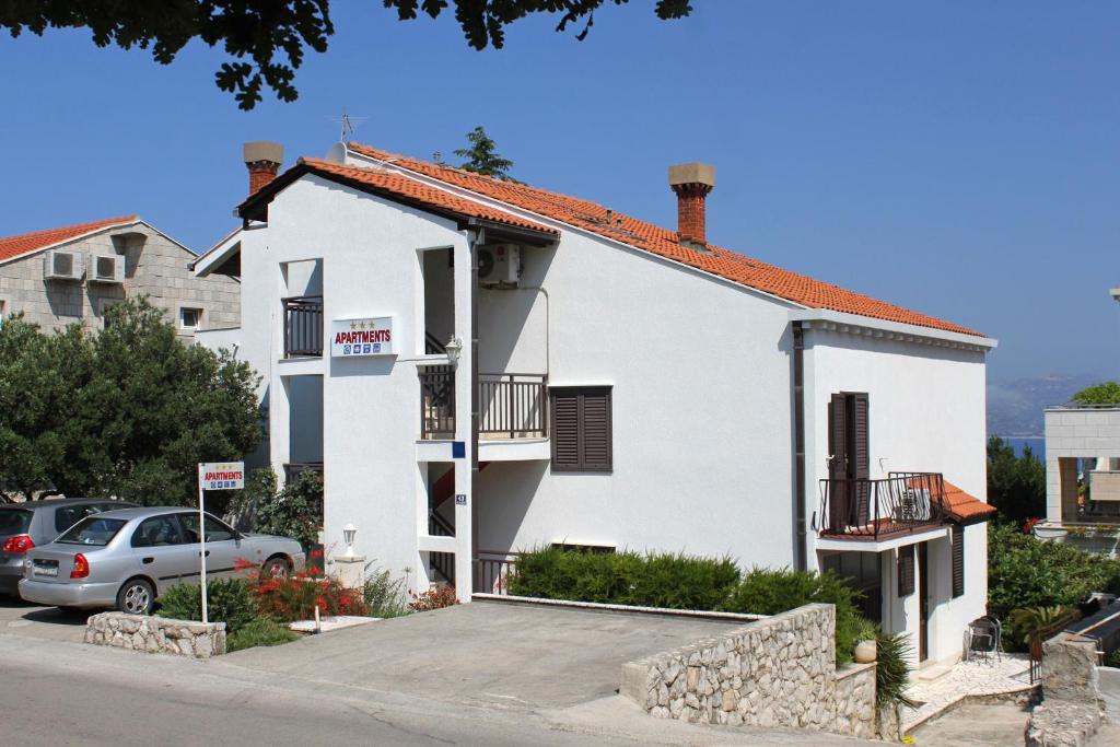 a white house with a car parked in a parking lot at Apartments with a parking space Cavtat, Dubrovnik - 8986 in Mlini
